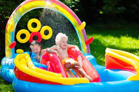 "Children playing and splashing in a colorful inflatable swimming pool on a sunny day."